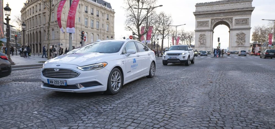 A self-driving vehicle from Mobileye’s autonomous fleet drives through the streets of Paris, with the Arc de Triomphe in the background.  (Credit: Mobileye)